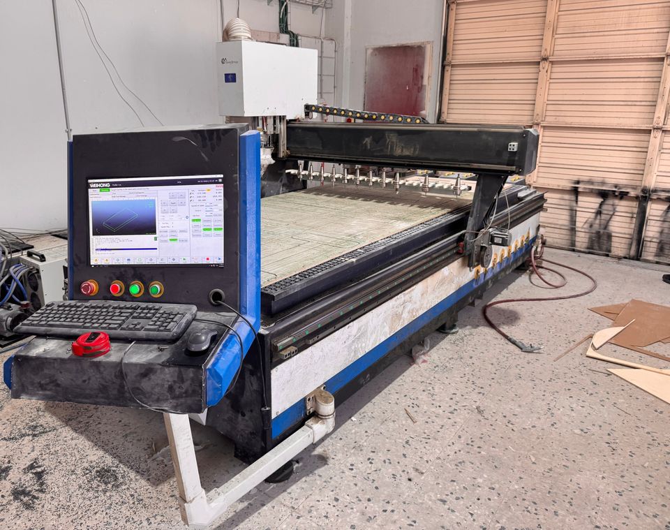 ראוטר CNC תעשייתי גדול עם לוח בקרה ומחסנית כלים להחלפה אוטומטית.